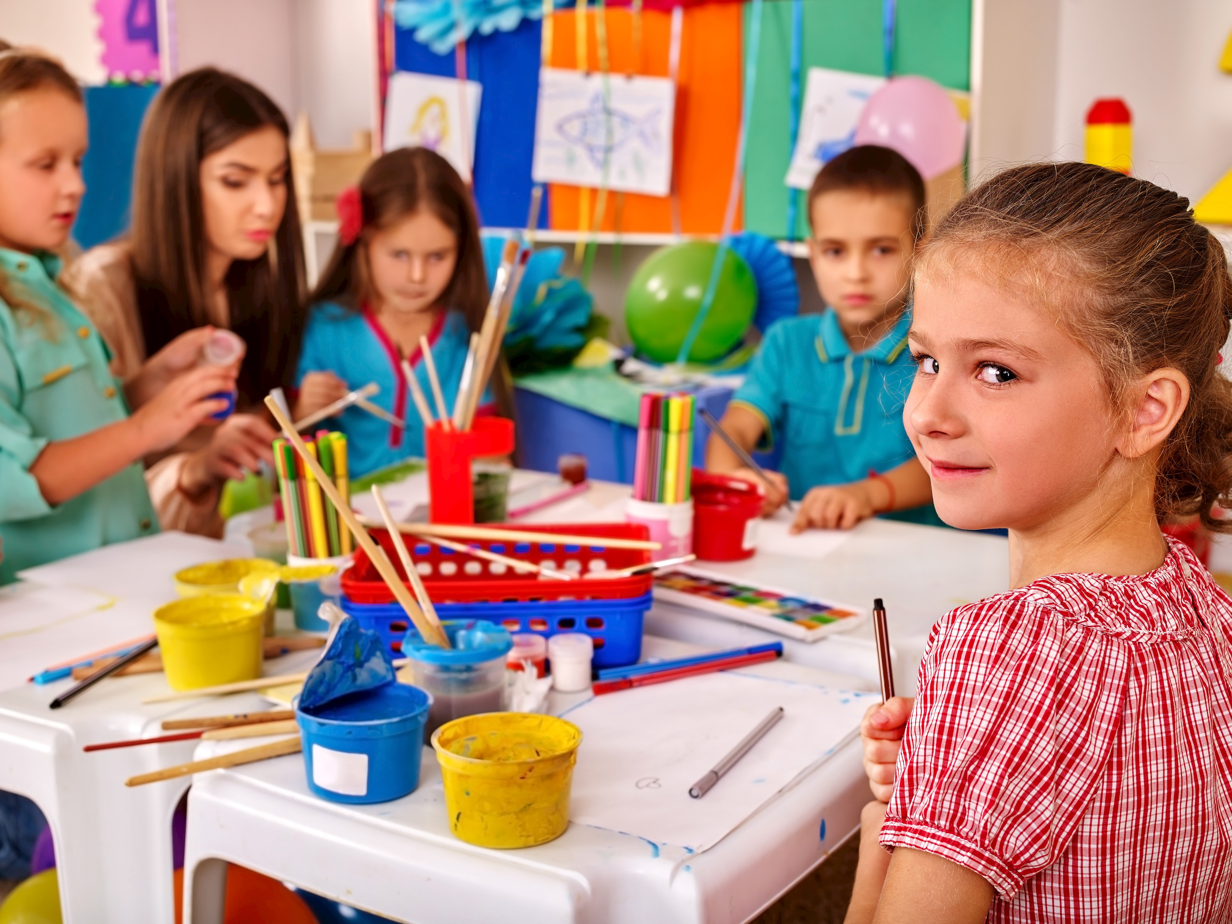 Eine Gruppe Kinder mit Erzieherin am Basteltisch