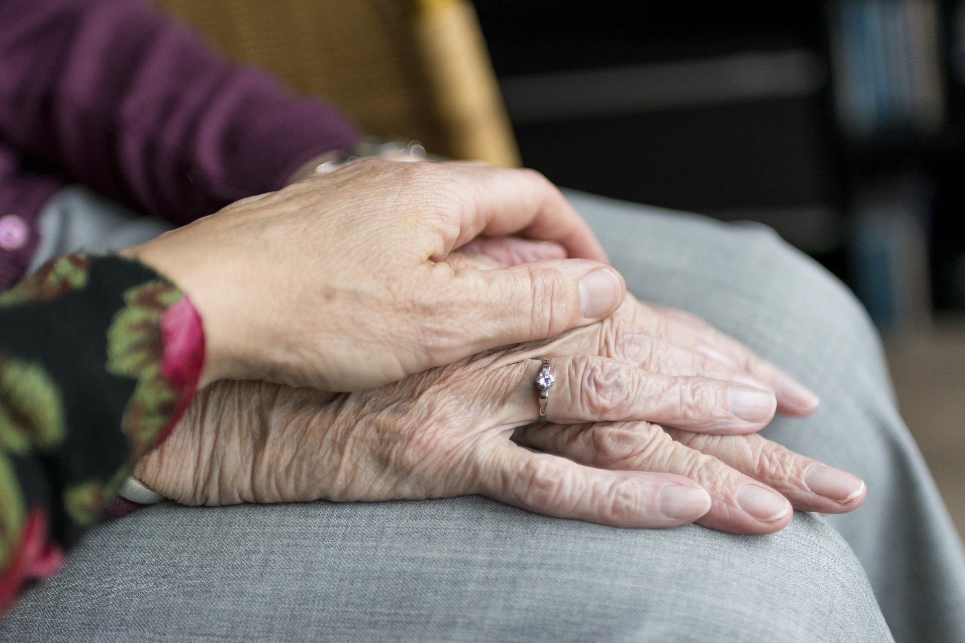 Ein Hand liegt auf den Händen von einer älteren Dame als Unterstützung